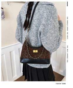 Detail of leopard print crossbody bag with gold lock and black chain strap worn by model