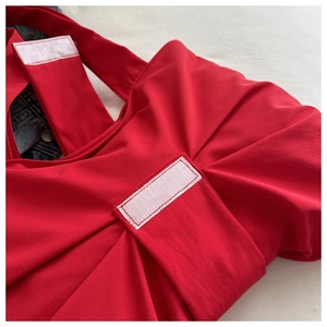 Close-up of red fabric shoulder bag featuring white hook-and-loop fastener detail