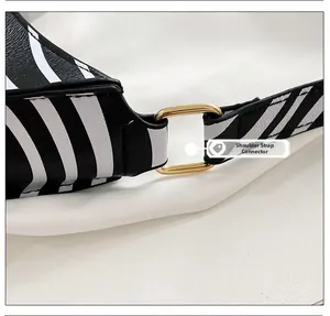 Detail shot of the gold metal strap connector on a black and white cow print bag