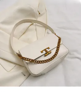 Detail of creamy white leather crossbody bag with gold logo and decorative chain strap