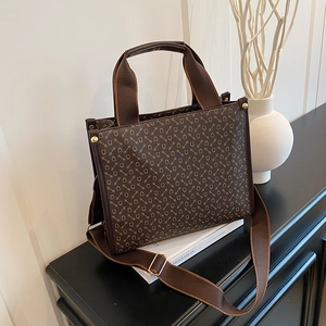 Brown tote bag with golden horsebit monogram and adjustable wide strap on book