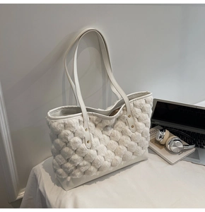 Dettaglio della borsa tote in peluche bianca con rivetti dorati e base in pelle di qualità