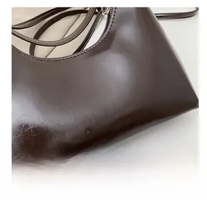 Detailopname van glanzende donkerbruine leren tas met reliëf van het woord FASHION