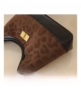 Detail of leopard print faux calf hair bag with gold metal buckle and black trim