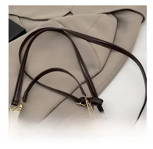 Detailopname van donkerbruine leren tasriem met gouden metalen gesp en ketting