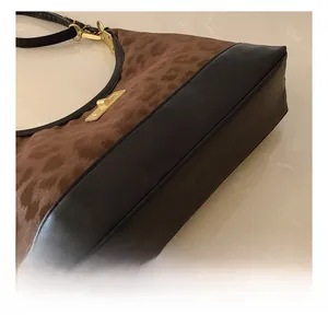 Detail of leopard print fabric and black leather stitching with gold metal buckle hardware