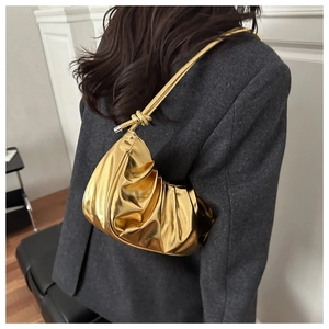 Dettaglio borsa a tracolla plissettata oro metallizzato con cinturino a nodo su blazer