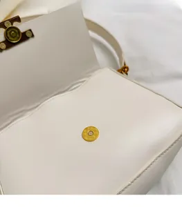 Close-up of cream white leather bag showing golden magnetic buckle and neat stitching