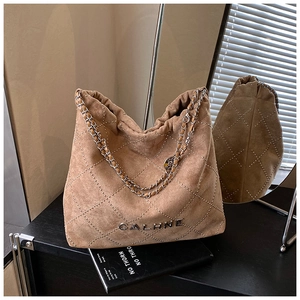 Detail of brown suede bucket bag featuring diamond rivet patterns and metal chain strap