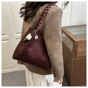 Detail of burgundy leopard print tote bag with woven handles and plush charm accessory