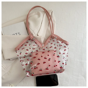 Detail of transparent PVC tote bag with cherry prints and pink leather inner pouch