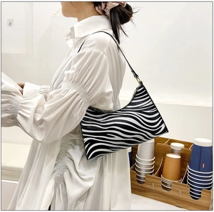 Chic zebra pattern hobo bag shown on a model with a stylish white puff-sleeve dress