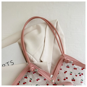 Dettaglio della borsa tote trasparente con stampa ciliegia e finiture in pelle rosa