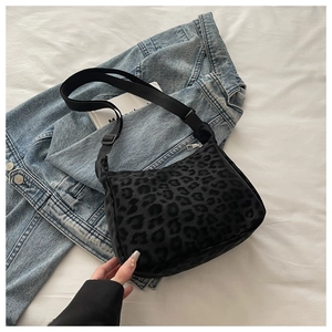 Detail of leopard print shoulder bag with adjustable strap on denim background