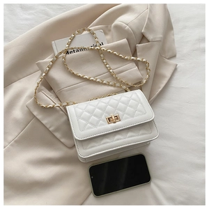 Detail of white quilted crossbody bag with gold chain strap and turn-lock closure