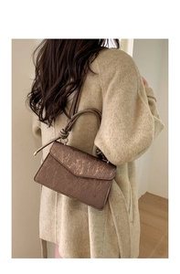 Rear view of model holding a vintage bronze envelope bag with vertical striped texture