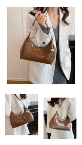 Detail van bruine hobo-tas met fashion reliëf en een gouden bolvormige hanger decor