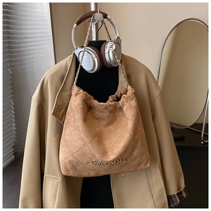Detail of brown suede bucket bag featuring diamond rivet patterns and metal chain strap