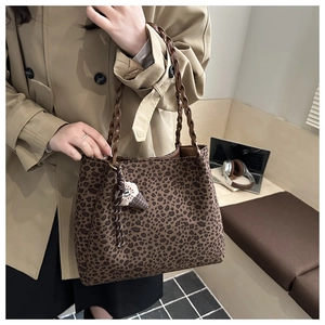 Detail of vintage leopard print tote bag with woven handles and plush charm accessory