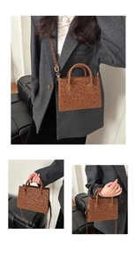 Close-up of leopard print handbag with dual handles and adjustable shoulder strap detail