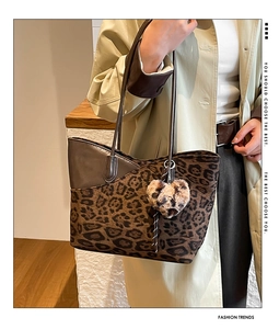 Close-up of leopard print tote bag with brown leather trim and plush heart charm