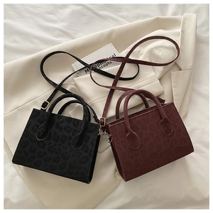 Close-up of leopard pattern texture on black and burgundy faux suede mini tote bags