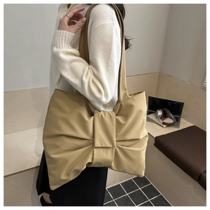 Lifestyle view of a khaki oversized bow shoulder bag on a minimalist wooden bench