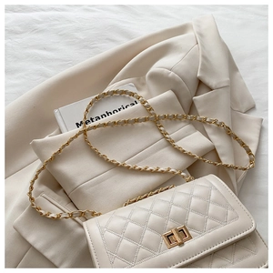Detail of quilted leather texture and golden metal twist lock on a beige crossbody bag