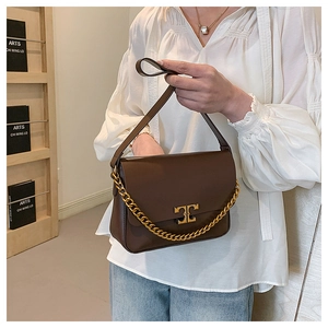 Detail of brown leather shoulder bag with gold chain and metal buckle closure