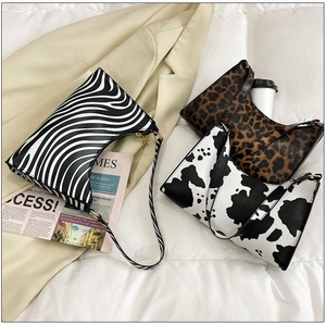 Three baguette bags in zebra, cow, and leopard prints with golden hardware detail