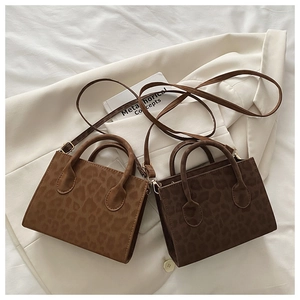 Detail view of leopard print crossbody bags in two shades on a white blazer
