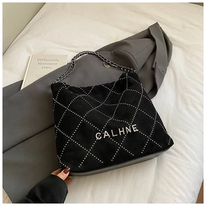 Detail of black quilted shoulder bag featuring silver chain strap and metal logo