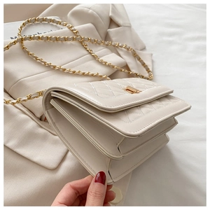 Detail of beige quilted flap bag with gold chain strap and elegant rectangular turn lock