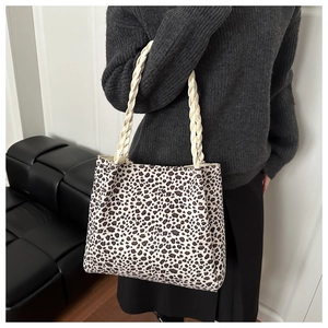 Detail of leopard print canvas tote bag featuring beige braided shoulder straps
