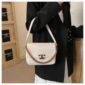 Detail of white leather shoulder bag with gold chain and metal buckle on elegant outfit