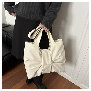 Dettaglio della borsa a spalla in nylon crema con fiocco e morbida trama plissettata e manico