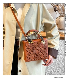 Dettaglio borsa vintage in pelle marrone con ricamo floreale e manico avvolto da foulard