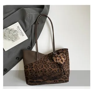 Detail of leopard print tote bag with brown leather paneling and plush heart charm