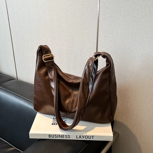 Sac cabas rétro marron avec bandoulière réglable posé sur un livre blanc