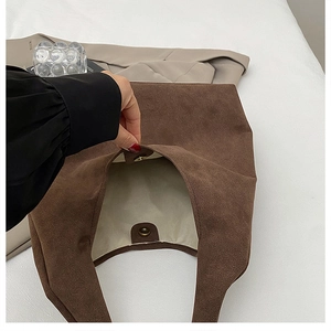 Detail view of the brown suede tote bag with gold magnetic buckle and fabric lining