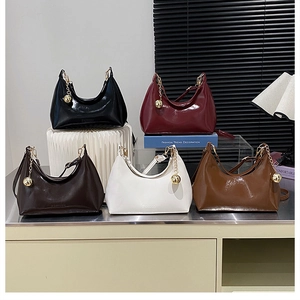 Détail de sacs demi-lune en cuir brillant de couleurs variées avec pendentif doré