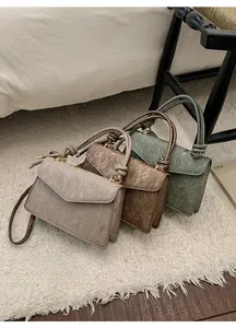 Detailed view of three textured leather mini bags in beige, brown and green colors