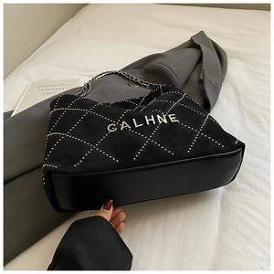 Detail of black quilted chain tote bag with metallic CALHNE logo and velvet texture
