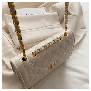 Detail of beige quilted chain bag with gold metal twist lock and leather strap