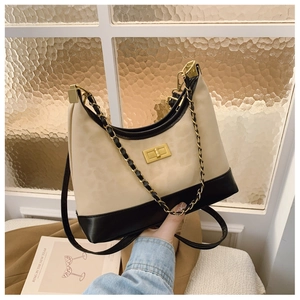 Detail of crossbody bag with beige leopard pattern, black trim and gold chain strap