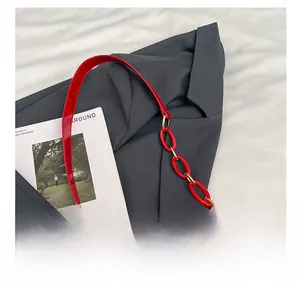 Detail of red crocodile pattern handbag featuring unique resin chain and leather strap