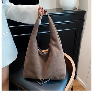 Detail of a vintage dark brown suede hobo tote bag on a stylish wooden armchair