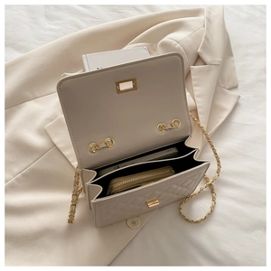 Detail view of the beige quilted crossbody bag showing dual interior compartments and gold lock