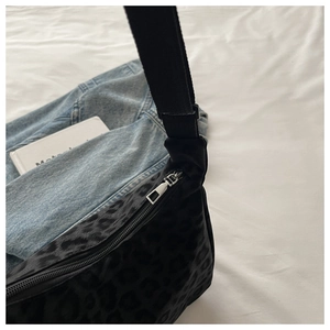 Detail of leopard jacquard fabric texture and silver metal zipper on black shoulder bag