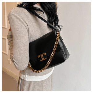 Detailed side view of black matte leather shoulder bag with bold gold chain strap and clasp